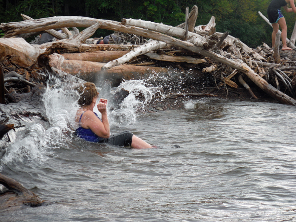 The waves are splashing against the logs and Karen.